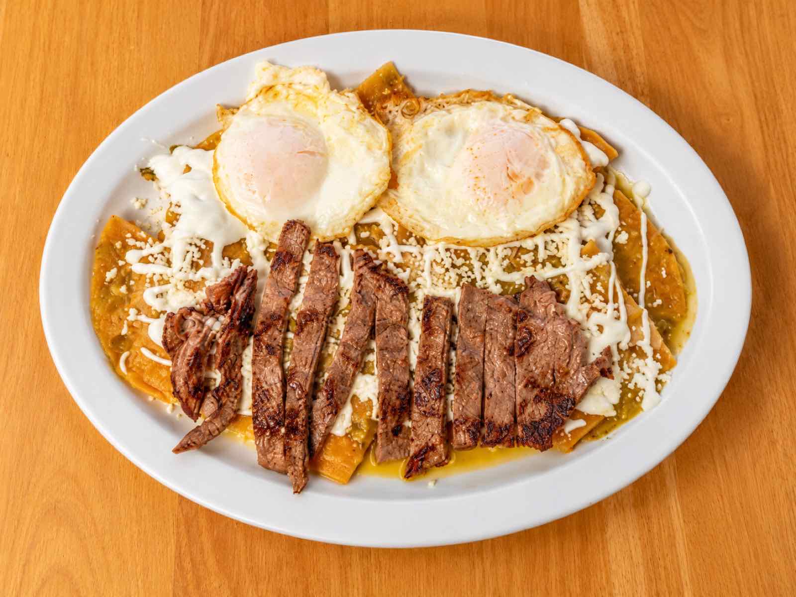 Chilaquiles verdes with carne asada and two fried eggs